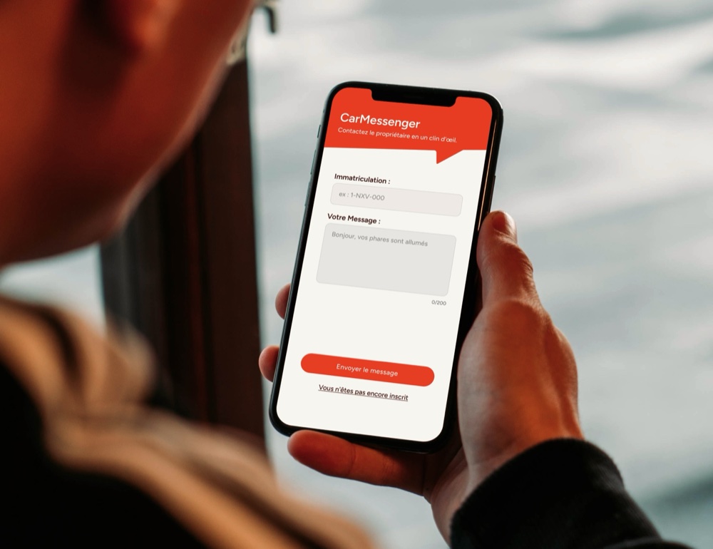 Main tenant un smartphone affichant l'interface CarMessenger avec un champ d'immatriculation et une zone de message pour contacter un automobiliste.